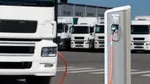 An electric truck recharges, with a fleet of electric trucks in the background. 